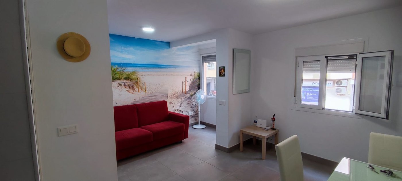 Salón del apartamento El Rinconcito Cubano en la Playa con sofá rojo y mural de playa